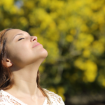 A woman with eyes closed head tilted toward the sun.